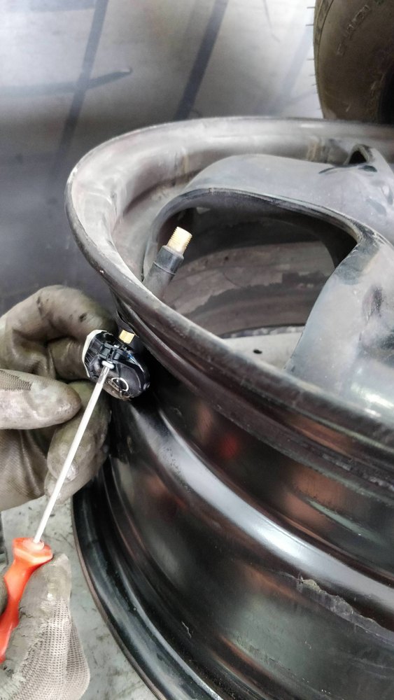 Tire pressure sensor being serviced inside a wheel